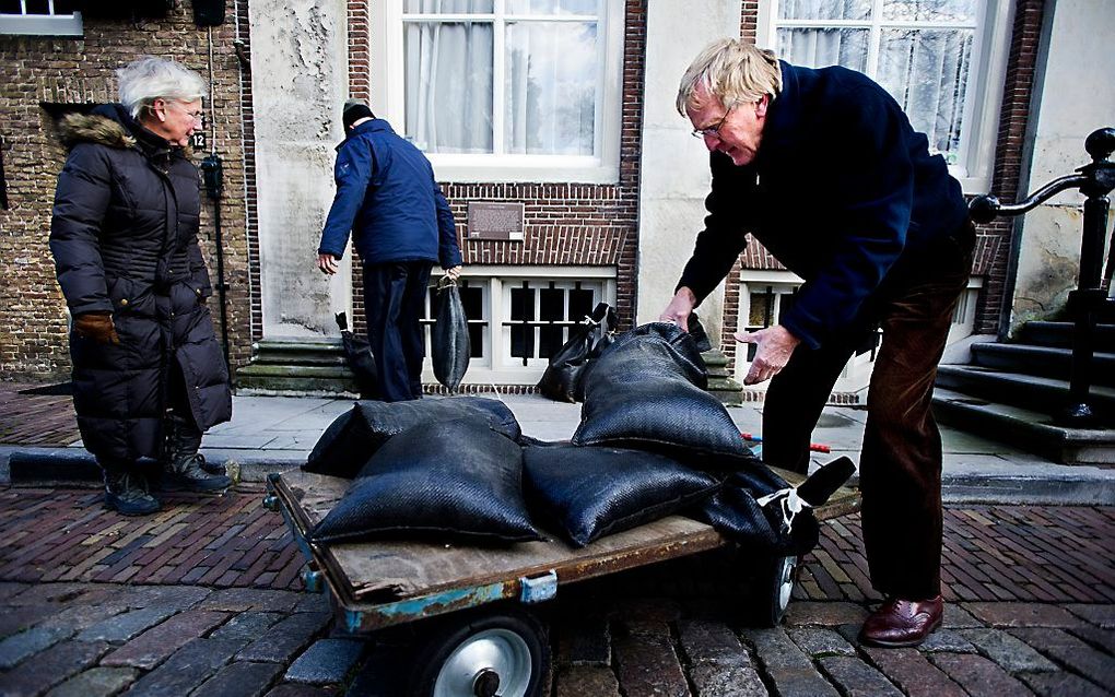 Bewoners van de Houtsteiger in het centrum van Dordrecht laden begin 2012 zakken zand op een karretje om de boel te beschermen tegen hoogwater. ANP