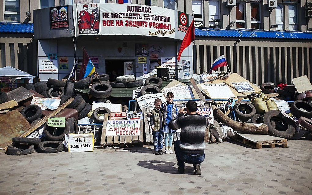 Een man fotografeert zijn kinderen in de Oost-Oekraïense stad Lugansk. beeld AFP