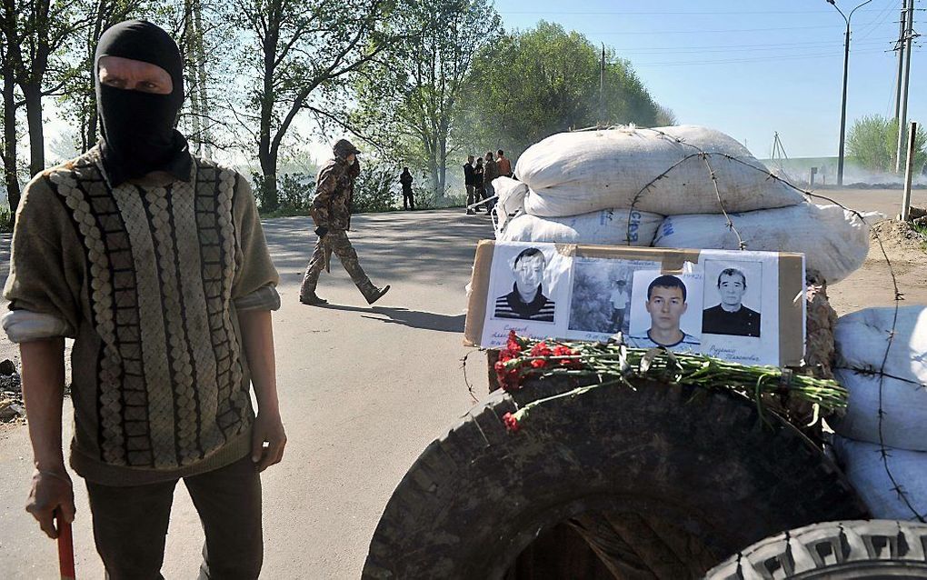 Pro-Russische activisten in Slavjansk bij een barricade waarop foto's van vier omgekomen kameraden zijn gelegd. De vier kwamen om bij een vuurgevecht met het Oekraïense leger. beeld AFP