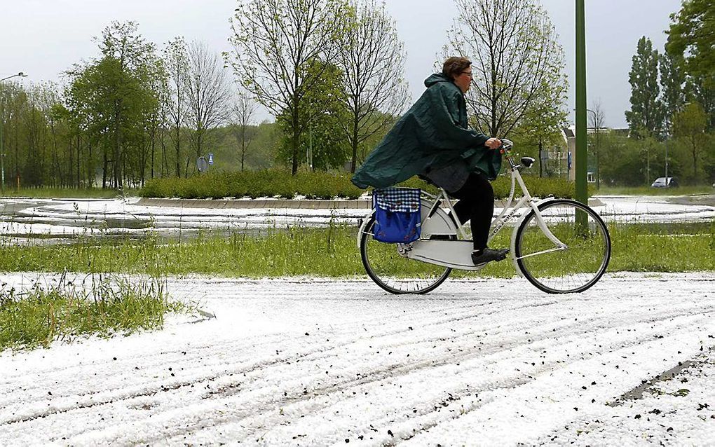 Een vrouw fietst over de Griftlaan in Zeist, die door een fikse hagelbui wit is gekleurd. Bij sommige stevige buien vielen soms hagelstenen van meer dan 2,5 cm groot. Heel de regio Utrecht had last van noodweer. Straten stonden blank en door blikseminslag