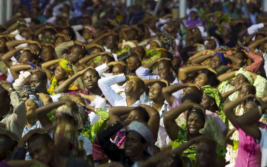 Onder leiding van een voorganger leggen bezoekers van een Nigeriaanse pinkstergemeente zichzelf de handen op om de zegen van God te ontvangen. beeld Andrew Esiebo