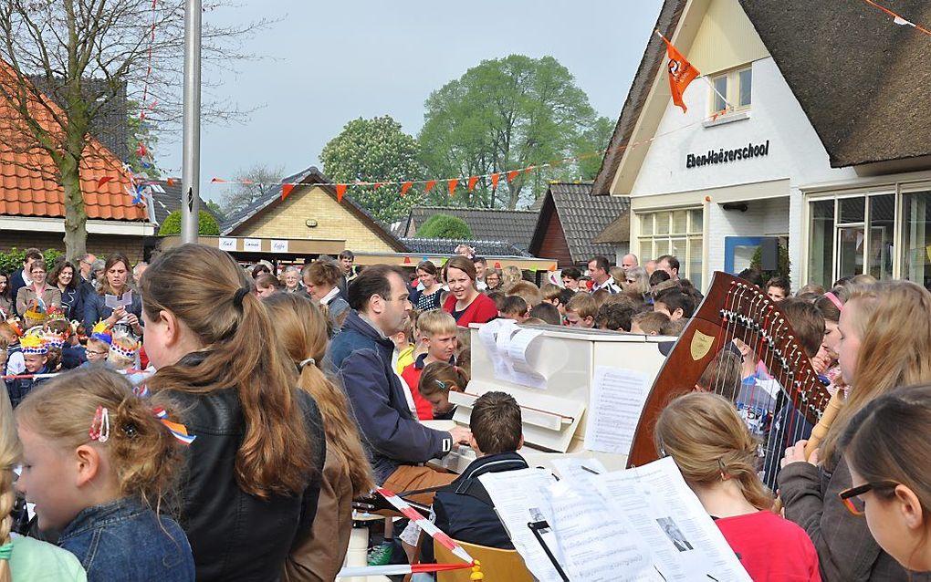 Voordat de koningsspelen beginnen, zingen jong en oud onder de vlag op de Eben-Haëzerschool in Elspeet. beeld A. Mulder