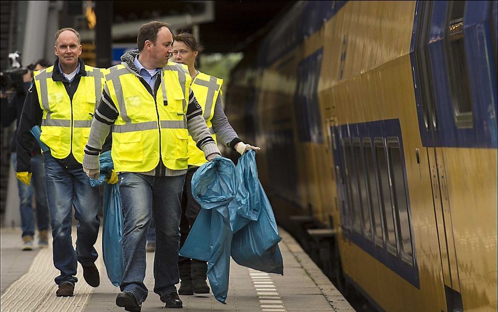 Medewerkers van de NS verlaten de trein met afvalzakken op het centraal station in Utrecht. beeld ANP