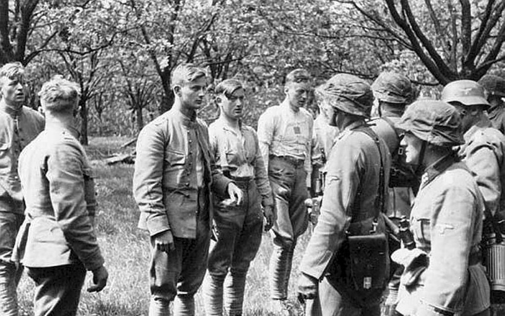 RHENEN. Nederlandse krijgsgevangen worden in mei 1940 na hun gevangenneming op de Grebbelinie ondervraagd door Duitse soldaten. beeld NIHM