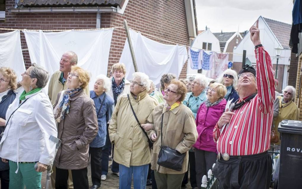 Gids Jaap Bakker vertelt zijn gehoor uit Zoetermeer graag smeuïge anekdotes over het Urker dorpsleven.  beeld Niek Stam