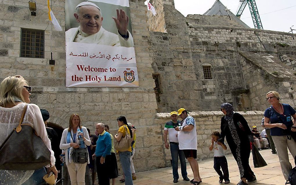 Toeristen in Bethlehem passeren een banner waarop paus Fransciscus wordt welkom geheten. beeld EPA