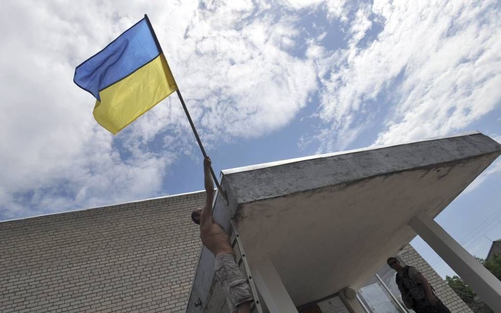 DONETSK. Een Oekraïense vlag wapperde zaterdag bij een stembureau in Donetsk. Separatisten voorkwamen de stemming in veel gevallen. beeld AFP