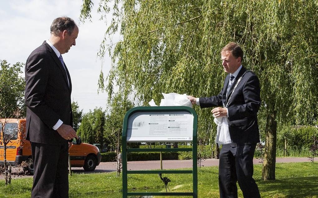 Onthulling van informatiepaneel over de kerkgeschiedenis van Reeuwijk door burgemeester Van de Kamp. beeld Peter Boon