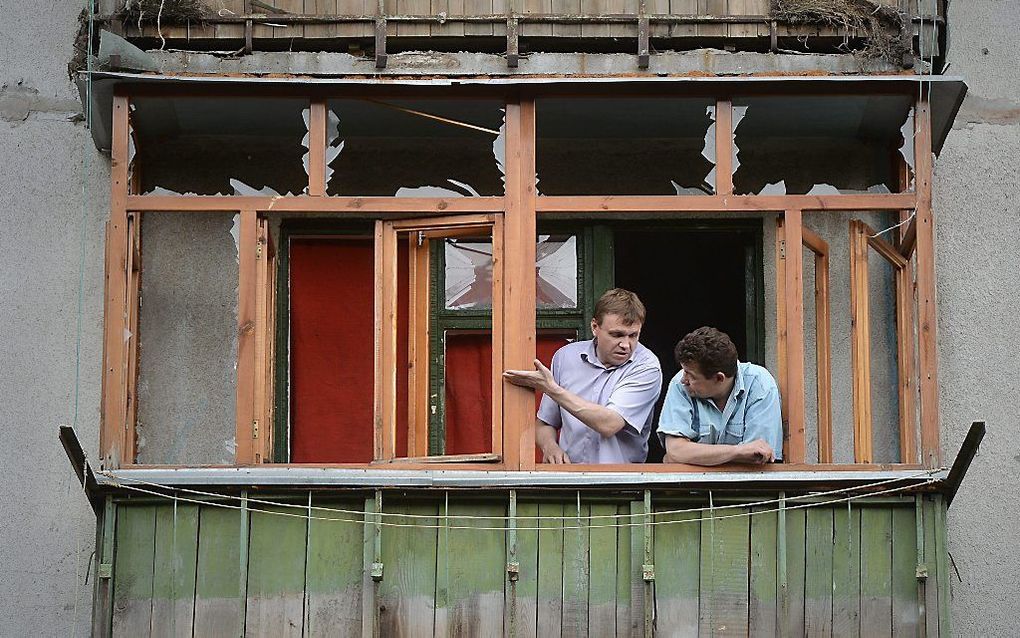 Mannen bekijken hun beschadigde huis in de buurt van Donetsk. Foto EPA