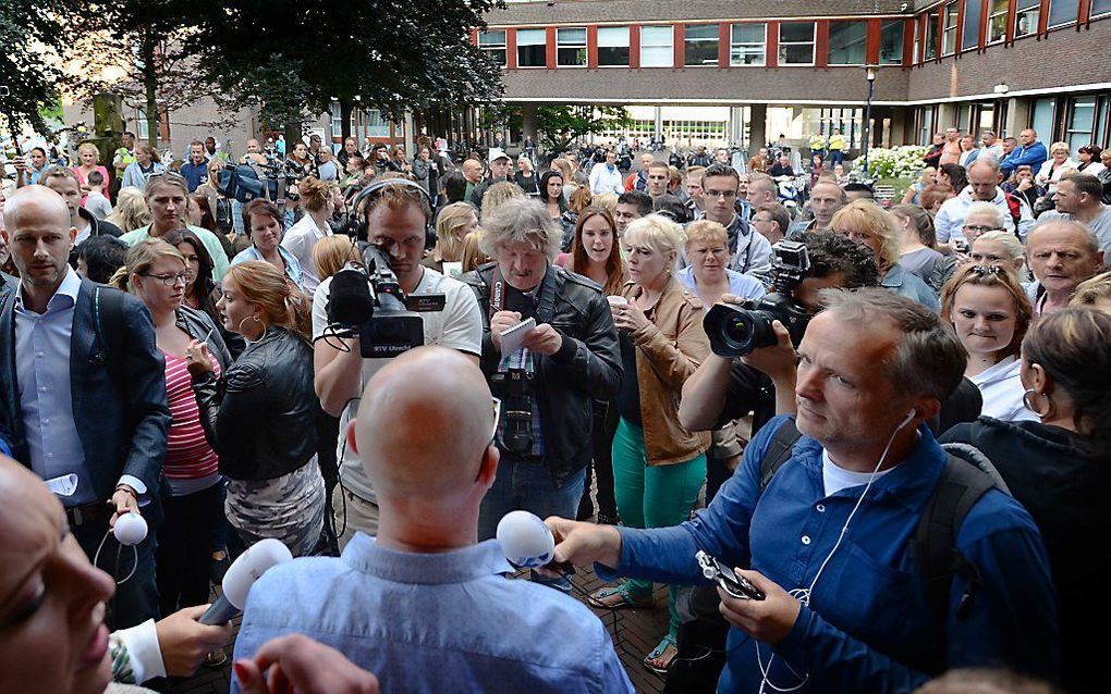 Een medewerker van de gemeente spreekt demonstranten toe die zich hebben verzameld voor het stadhuis. Foto ANP