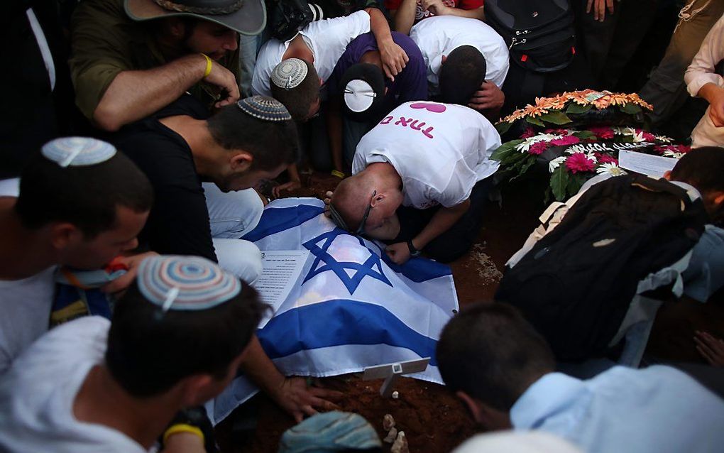 Vrienden van een van de vermoordde Israëlische jongeren buigen zich in diepe rouw over zijn graf. beeld EPA