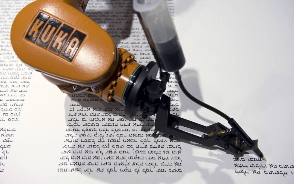 Een robotarm zwenkt van rechts naar links over het papier en schrijft op deze manier de Hebreeuwse tekst van de Thora over. De installatie is sinds gisteren te zien in het Jüdisches Museum in Berlijn. Beeld AFP