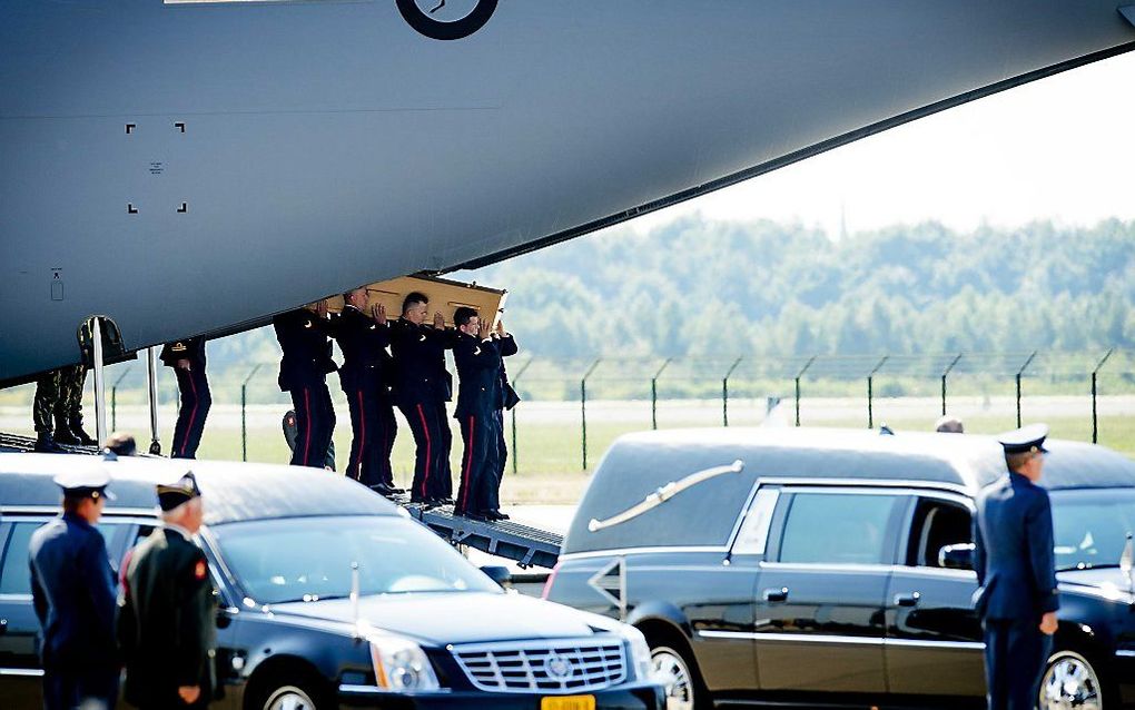 Militairen dragen op vliegbasis Eindhoven een kist met daarin een van de lichamen van de slachtoffers van de vliegramp in Oekraïne. beeld ANP