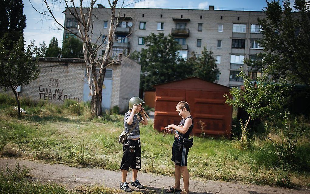 Jongens spelen met een legerhelm in Donetsk. Foto EPA