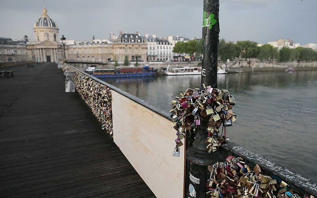 Een houten schot op de plaats waar een stuk van de brug van de Pont des Arts bezweek onder de vele sloten. Foto AFP