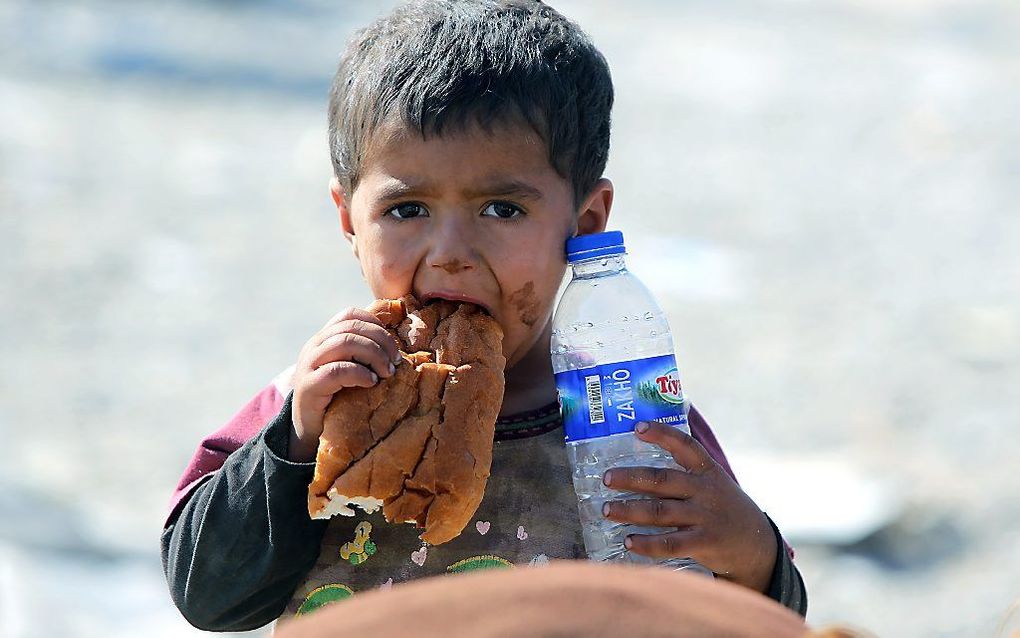 Een Iraaks jongentje ontvangt brood en water nadat hij over de grens is gevlucht. Foto AFP