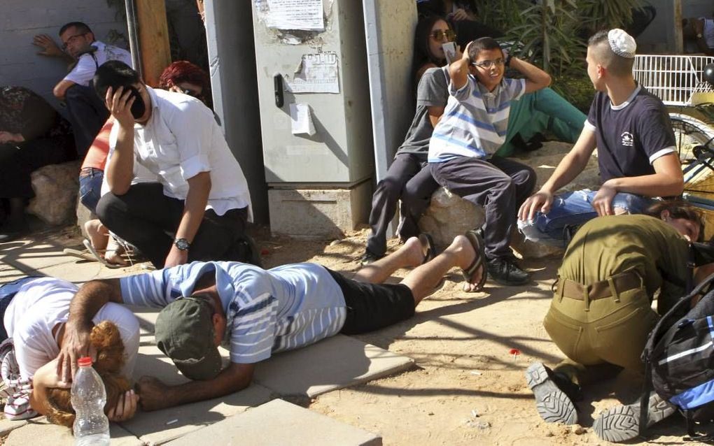 Inwoners van Netivot, een dorp in de Eshkolregio, duiken weg voor raketten vanuit Gaza, tijdens de begrafenis van de Israëlische soldaat Meidan Maymon Biton, 29 juli. beeld AFP