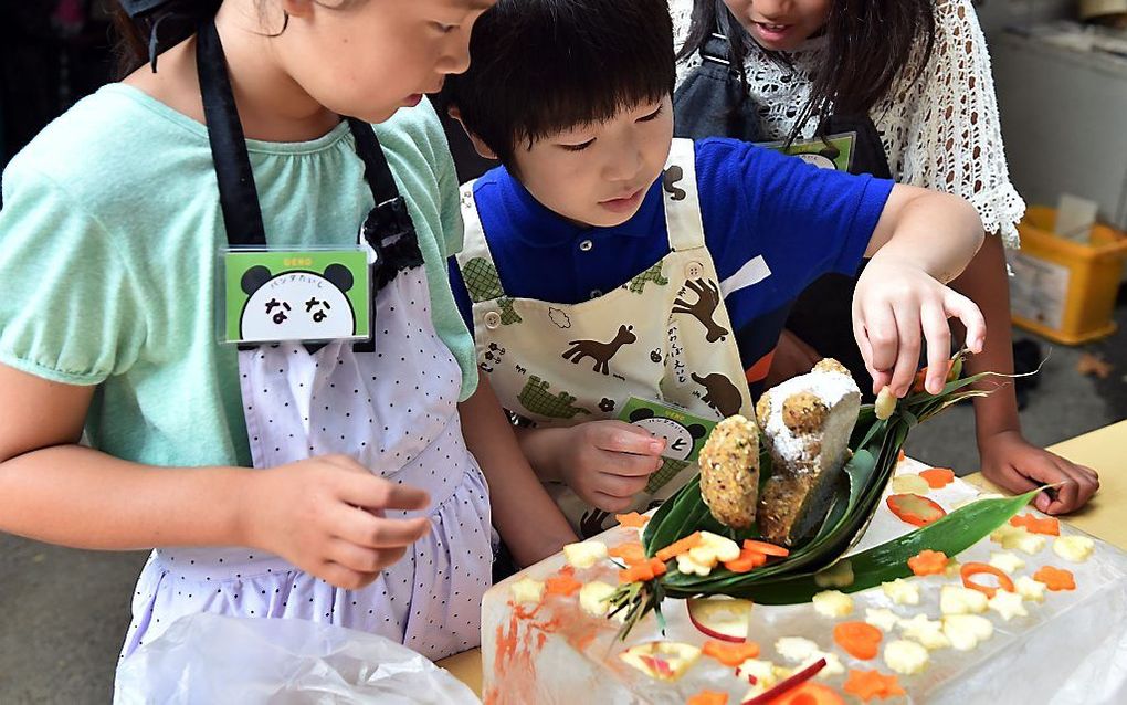 Schoolkinderen maken in een dierentuin in de Japanse hoofdstad Tokio een taart voor de jarige pandabeer Ri Ri. beeld AFP