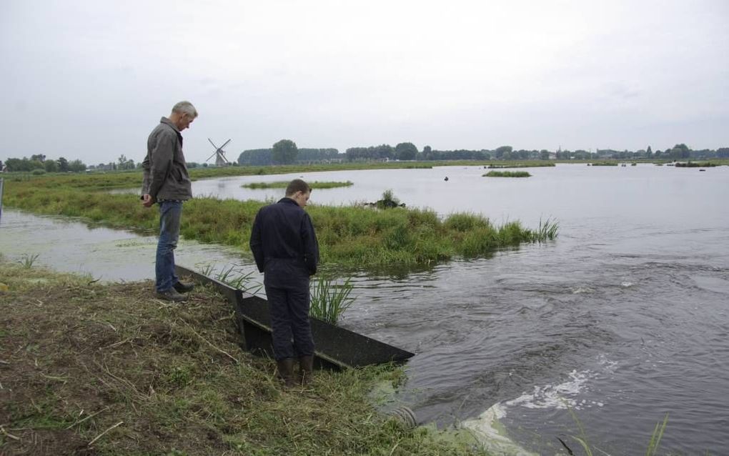 HAASTRECHT. Omwonenden tonen belangstelling voor de waterinlaat, waaruit per minuut ruim 20 liter water vanuit de Vlist in het waterbergingsgebied de Hooge Boezem bij Haastrecht stroomt. Op de achtergrond Boezemmolen nummer 6. beeld RD