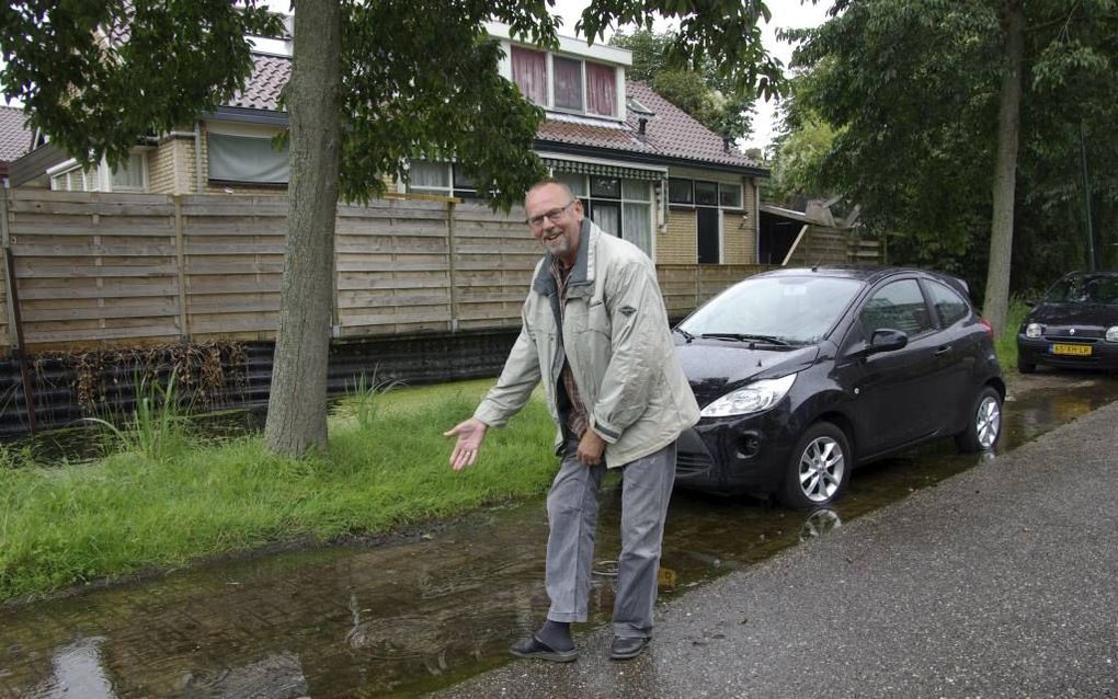 KANIS. Joop Bouwman bij de plassen op de hoek van de Roerdompstraat in het Utrechtse dorpje Kanis. Die staan even hoog als de sloot erachter. Als Bouwmans buren uitstappen, staan ze „tot aan de enkels” in het water. beeld RD