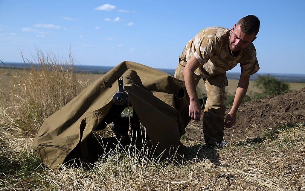 Een Oekraïense militair camoufleert een machinegeweer. beeld AFP