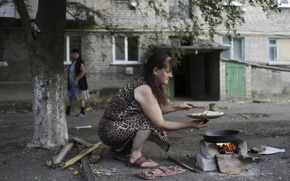 Een vrouw kookt op een kampvuurtje. Het Internationale Rode Kruis noemt de humanitaire situatie in Oost-Oekraine kritiek. Beeld AFP