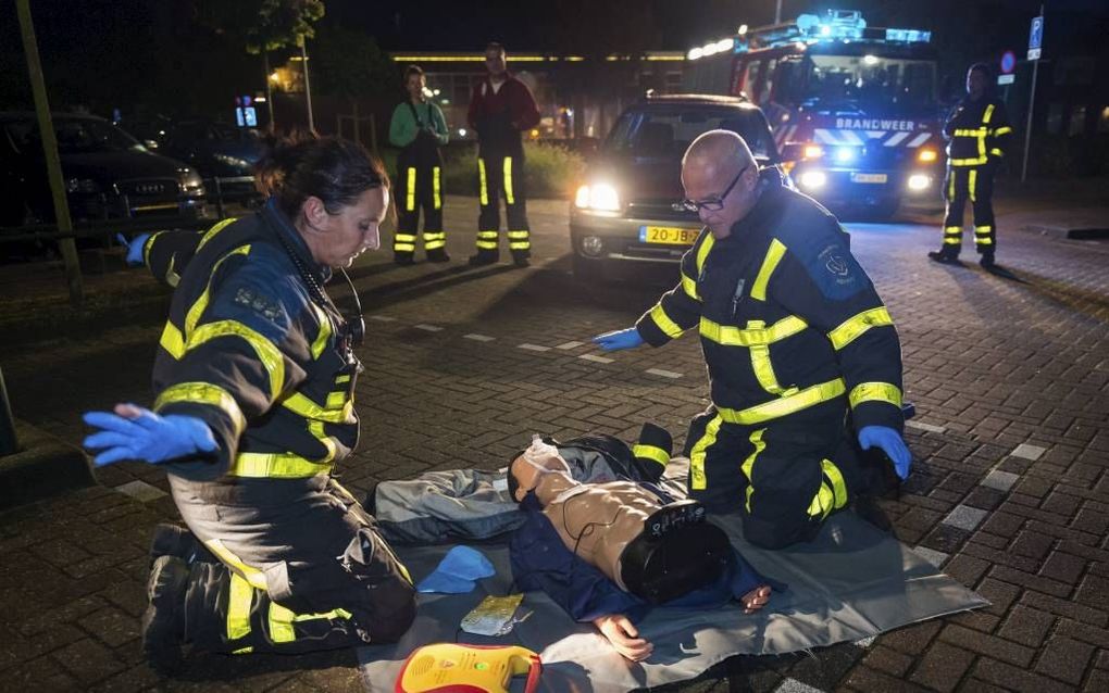 ZUID-BEIJERLAND. Brandweerlieden Anique (l.) en Jo houden hun armen gestrekt, omdat het AED-apparaat waarschuwt dat het het ‘slachtoffer’ en schok toedient. De brandweer Zuid-Beijerland oefende woensdagavond op straat. Het korps zoekt naarstig naar een ze