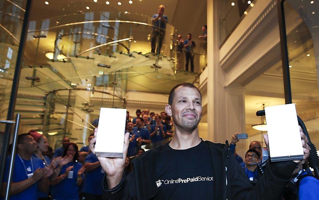 De eerste klant komt naar buiten met zijn nieuwe iPhone 6, na aanschaf in de Apple Store in Amsterdam. beeld ANP