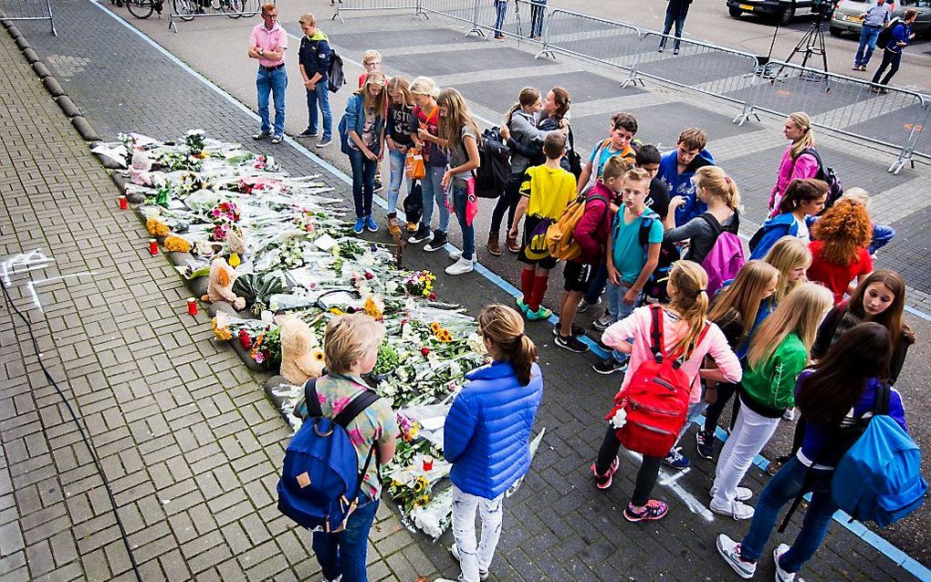 Belangstellenden staan bij de bloemen ter nagedachtenis aan de slachtoffers van het ongeluk met een monstertruck. Beeld ANP