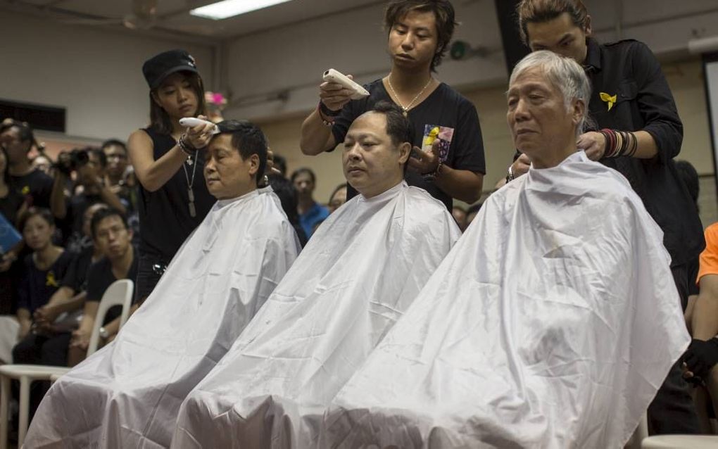 HONG KONG. De leiders van Occupy Central in Hong Kong laten zich uit protest kaalscheren. Rechts: Baptistenpredikant Chu Yiu-ming. beeld EPA