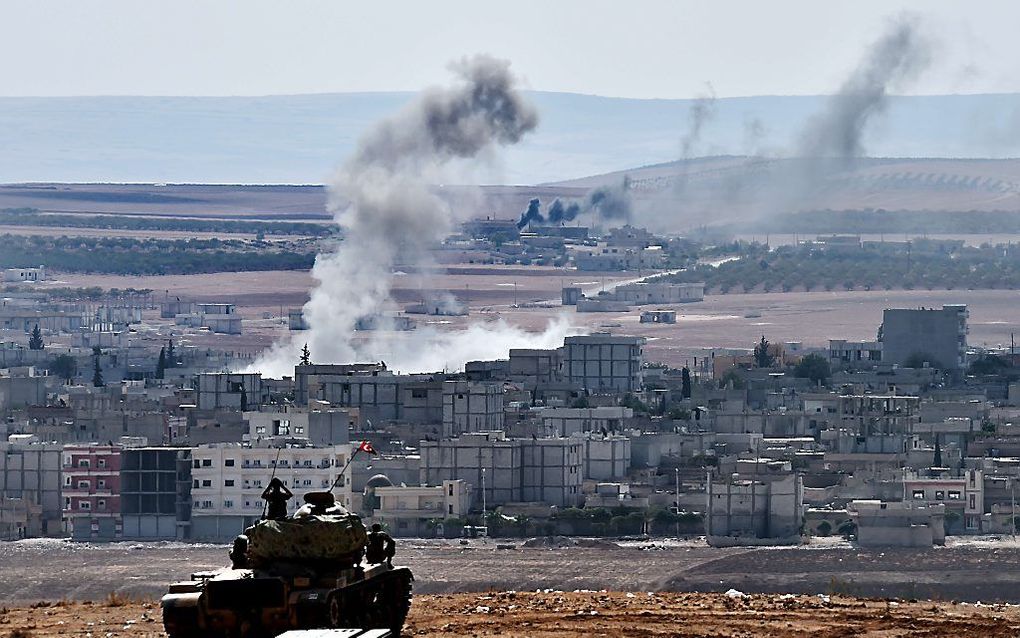 Turkse militairen kijken vanaf een heuvel naar de strijd in Kobani. Beeld AFP