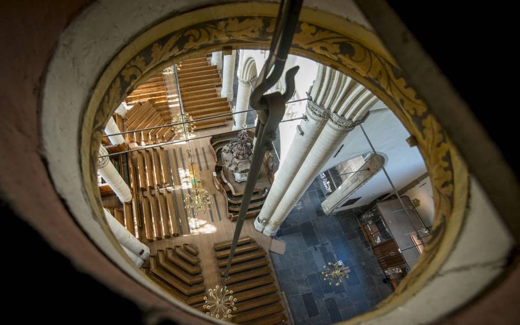 Bezoekers kregen deze week een rondleiding op de zolder van de Dordtse dom. Vanuit het gat is de grootste kroonluchter in de kerk te zien; in het midden, rechts, de preekstoel. Beeld Cees van der Wal