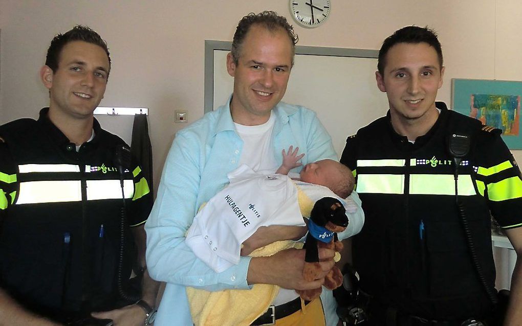 De trotse vader poseert met zijn zoon Thomas en de agenten die assisteerden bij de geboorte van de baby. beeld ANP