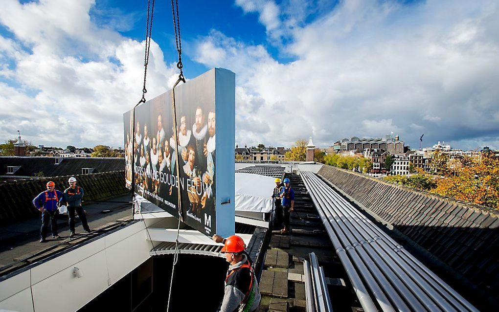 Een schilderij gaat, ingepakt en wel, door een gat in het dak van de Hermitage. Met een hijskraan worden maandag 15 immense groepsportretten uit de 17e eeuw via het dak naar binnen gebracht. Beeld ANP