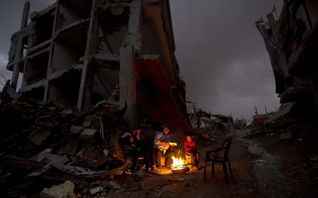 Palestijnen rond een vuurtje voor hun gebombardeerde huizen. Beeld AFP