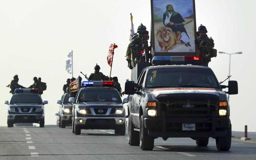 NAJAF. Iraakse militairen rijden door Najaf met de beeltenis van een sjiietische imam. beeld AFP