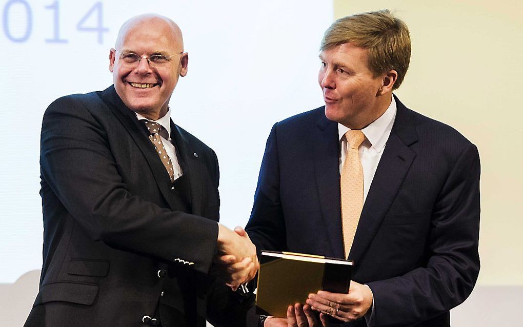 Koning Willem-Alexander krijgt het eerste exemplaar overhandigd van het jubileumboek.  beeld ANP