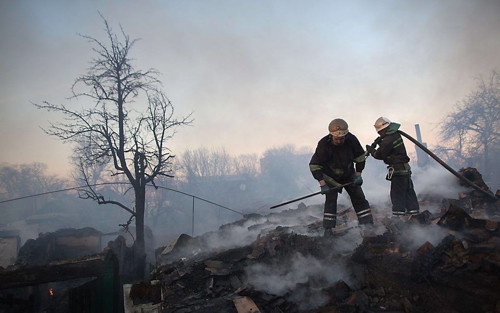 Brandweerlieden bestrijden een brand als gevolg van artilleriebeschietingen nabij het vliegveld van Donetsk. Beeld AFP