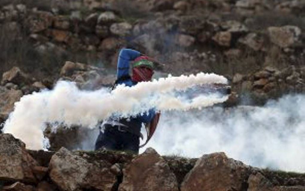 Een Palestijnse Hamasstrijder bestookt Israëlische militairen met traangas tijdens ongeregeldheden OP de Westbank, vorige maand. Beeld AFP