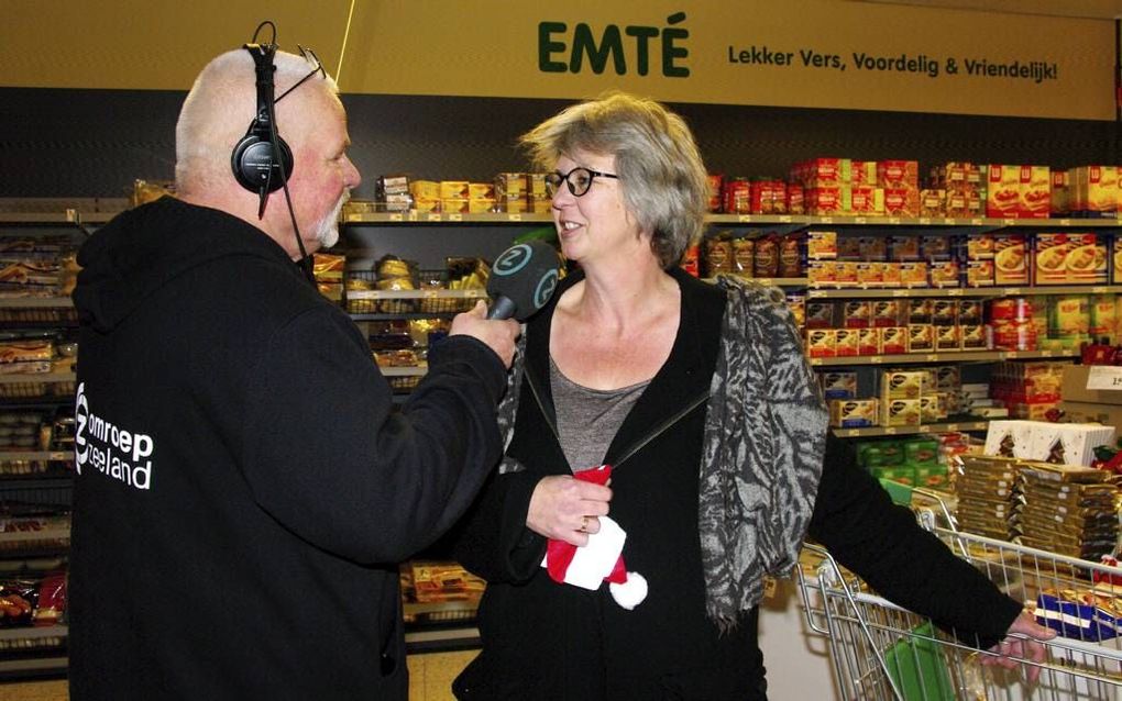 Verslaggever René van der Vliet interviewt Tinka Leene, die 300 pakjes kerstkransen schonk. beeld Van Scheyen Fotografie.