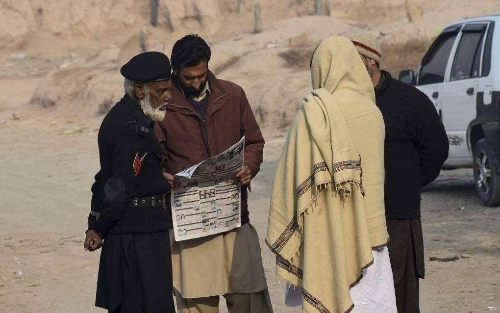 PESHAWAR. Inwoners van de Pakistaanse stad Peshawar houden elkaar op de hoogte van het nieuws over de aanslag op een school in hun woonplaats. beeld AFP