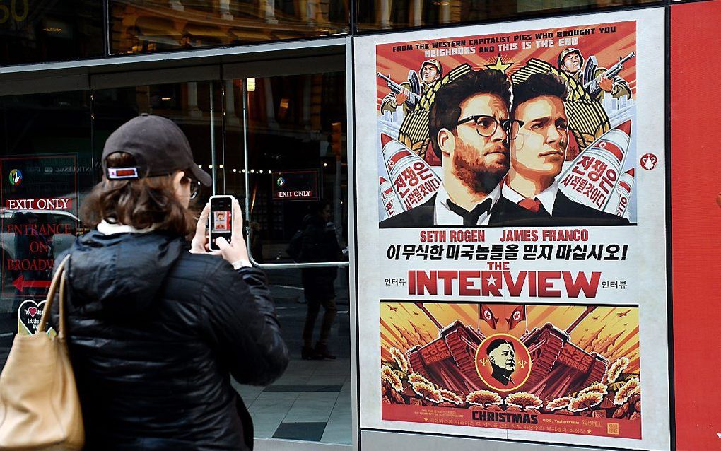 NEW YORK. Een passant in New York maakt een foto van een poster die de komische film over Noord-Korea ”The Interview" aankondigt. De producent Sony heeft besloten de film niet op de markt te brengen na cyberaanvallen op zijn computers. beeld EPA