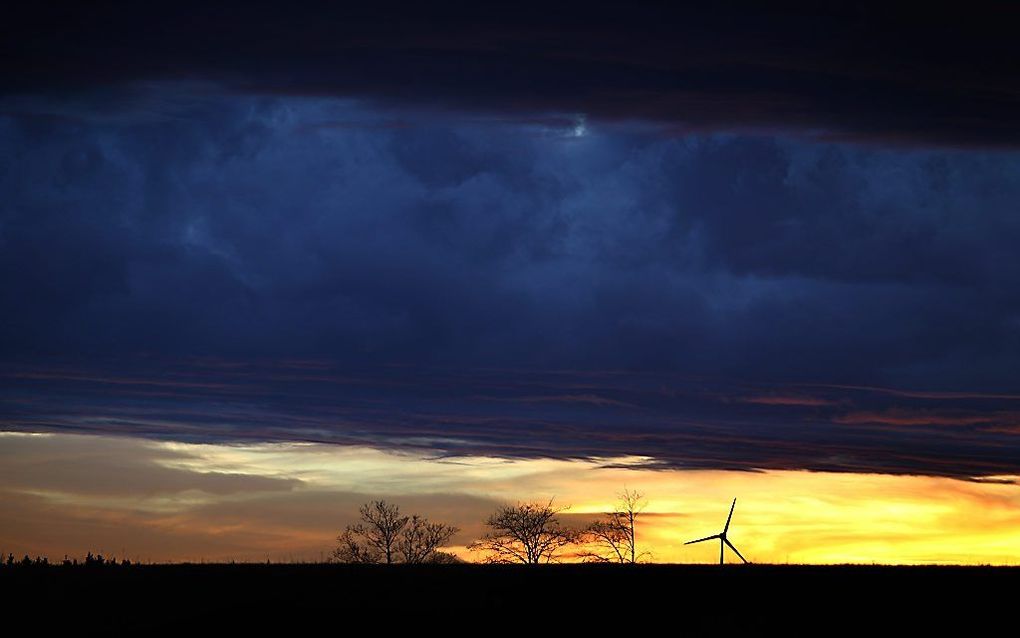 Een windmolen steekt scherp af tegen de horizon. De foto is afgelopen weekeinde genomen in Friesenried, Duitsland. Beeld EPA