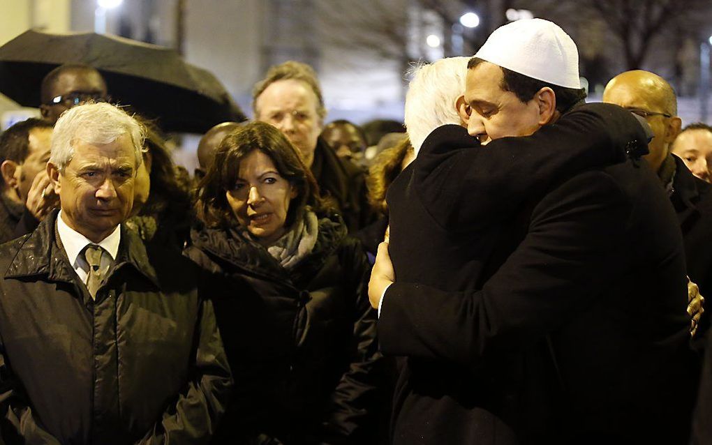 Demonstratie op zaterdagavond in Parijs, waarbij een imam iemand omhelst. Ook de burgemeester loopt mee. Beeld AFP