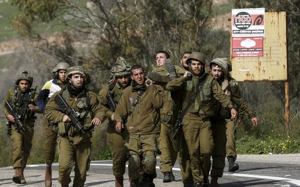 Israëlische militairen droegen gisteren het lichaam van een gewonde kameraad na de schotenwisseling met Hezbollah op de Golanhoogvlakte. Daarbij kwamen twee militairen om het leven. beeld EPA