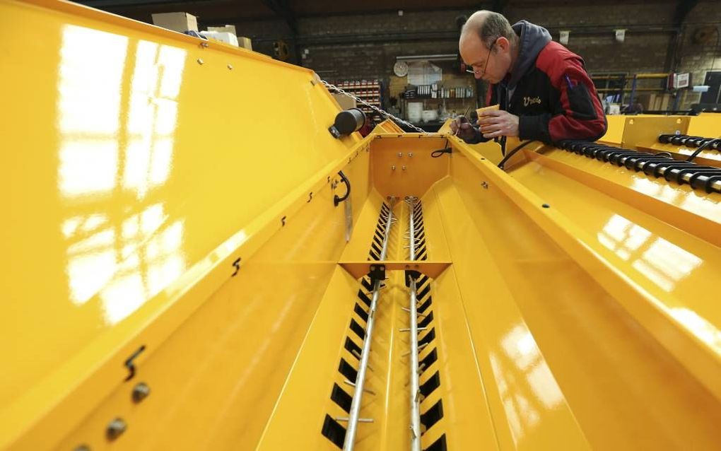 DODEWAARD. Fabrikant Vredo in Dodewaard maakt overuren om aan de vraag naar doorzaaimachines voor grasland te voldoen. Veel Friese boeren laten land doorzaaien, dat door de muizenplaag is aangetast. Foto: een medewerker van Vredo sleutelt aan een onderdee