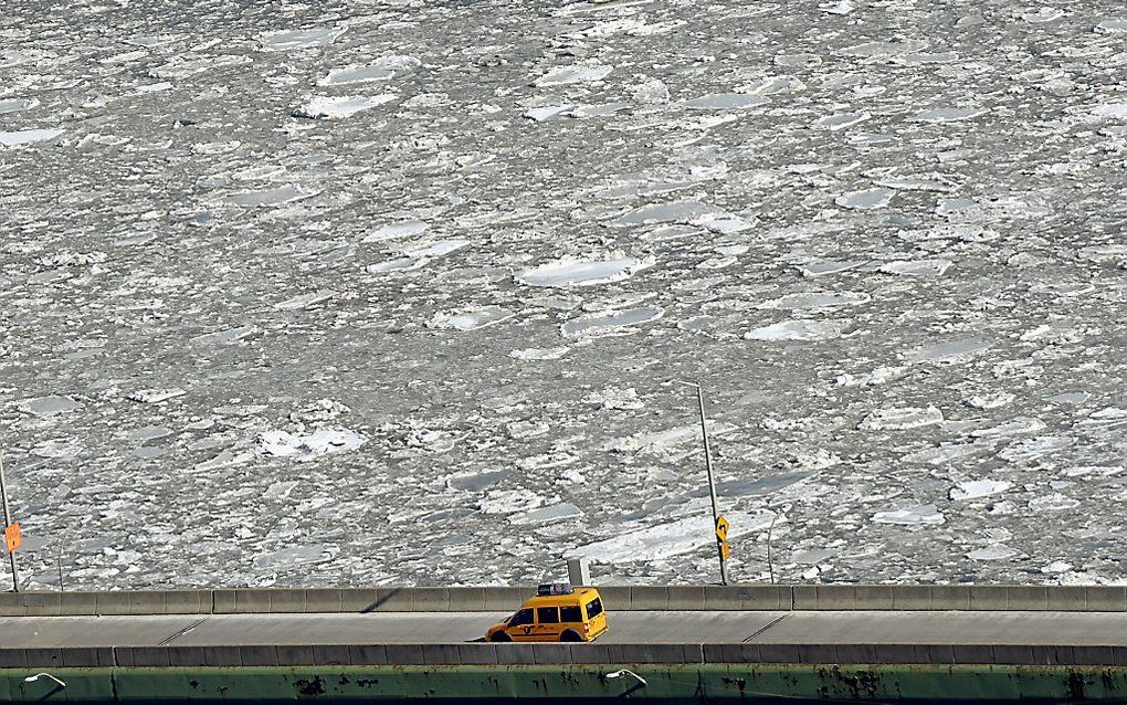 Een taxi in New York rijdt langs een met ijsschotsen gevulde East River in New York. beeld AFP