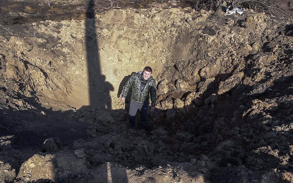 Een inwoner van het Oost-Oekraïense dorp Nikishyno in een krater. beeld EPA