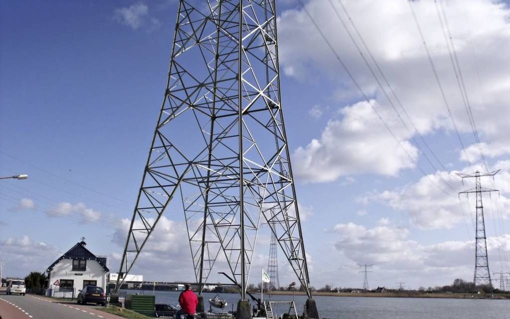 De dijkwoning van familie De Waard in de Lekkerkerkse buurtschap Schuwacht staat pal naast een hoogspanningsmast. Op de bedrading boven hun hoofd staat 380.000 volt. beeld Dick den Braber