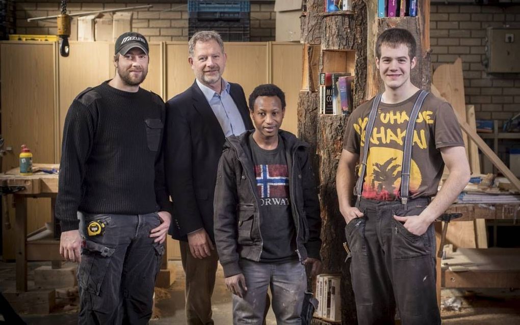 Initiatiefnemer Tom van den Belt met medewerkers van Ons Bedrijf bij de afgelopen week door hen vervaardigde ‘boekenbomen’, bedoeld voor het particulier uitwisselen van boeken. beeld Niek Stam